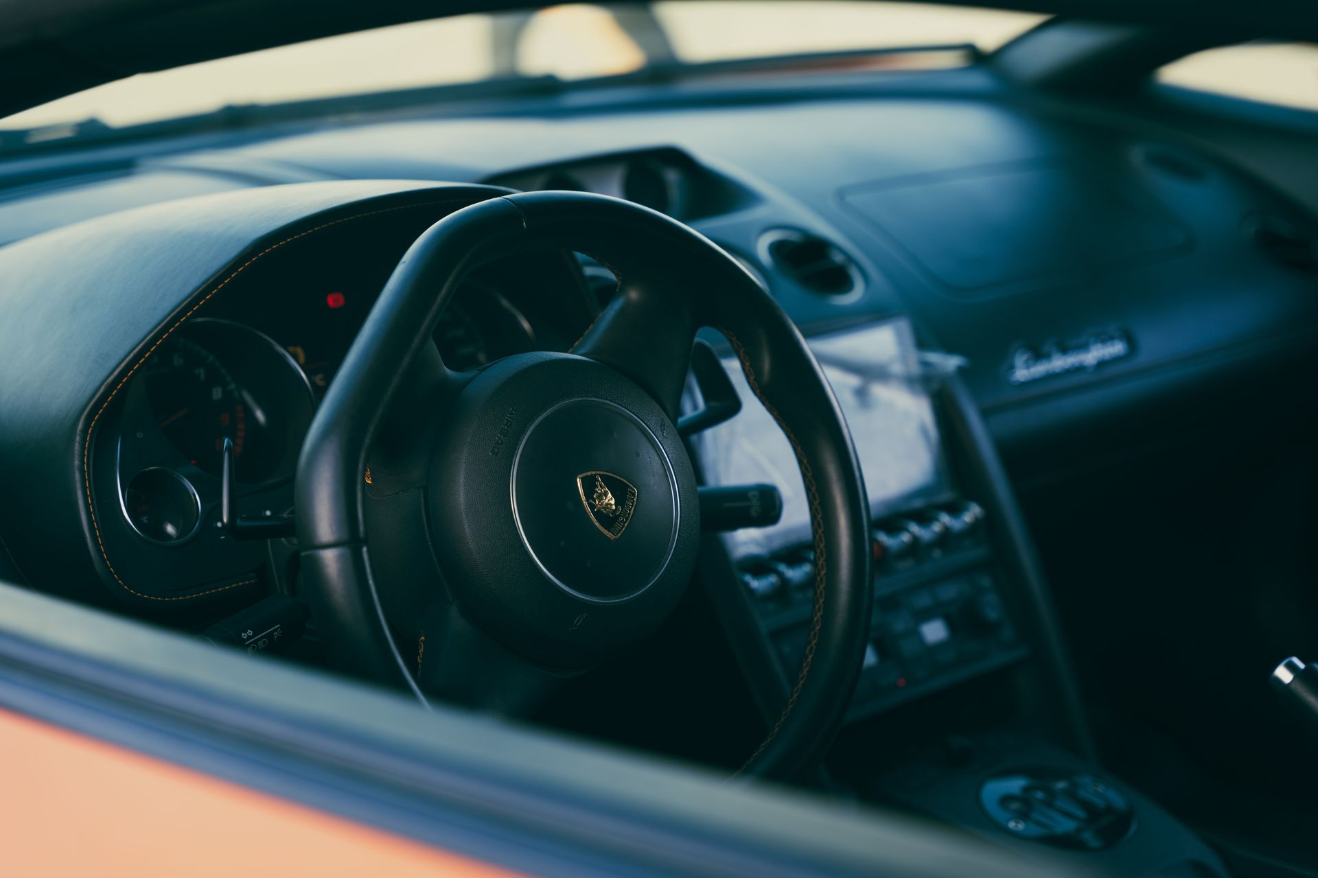 Close-up view of a luxury Lamborghini car steering wheel, showcasing intricate design details and sleek interior.